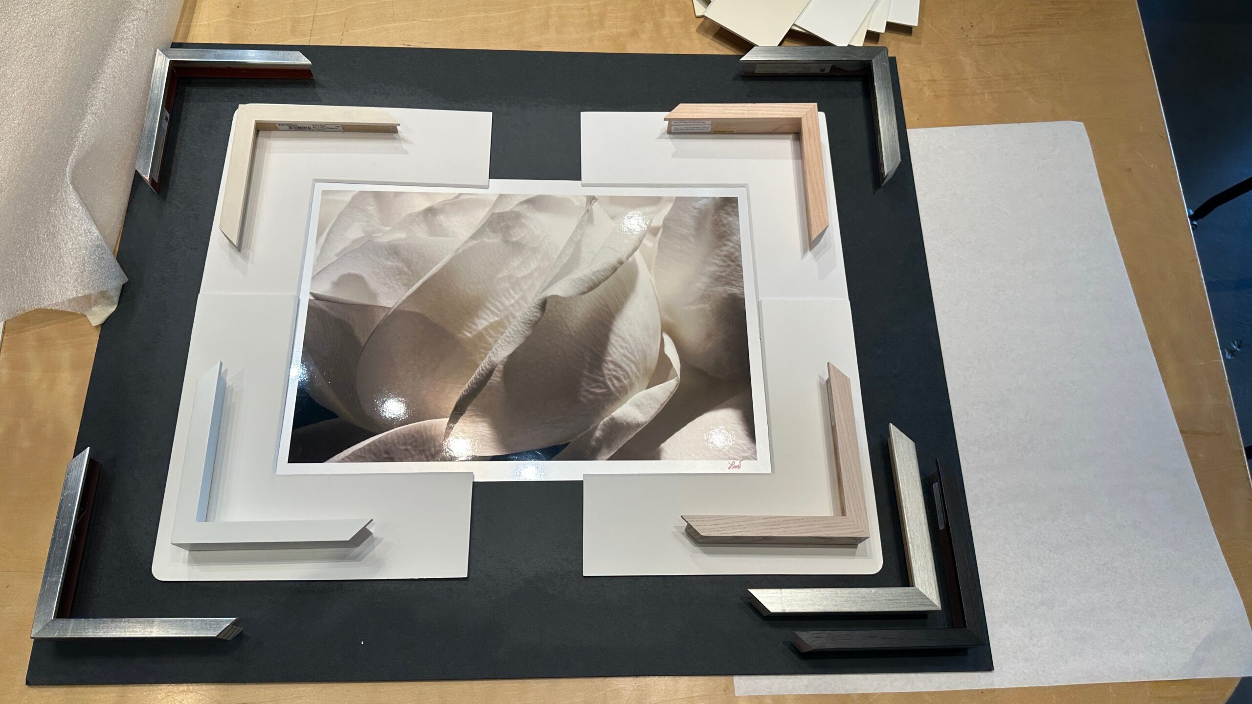 Artwork, frame samples and matting options being reviewed at the design table